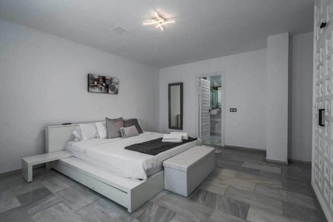 A modern bedroom with a bed, bench, and a walk-in closet.
