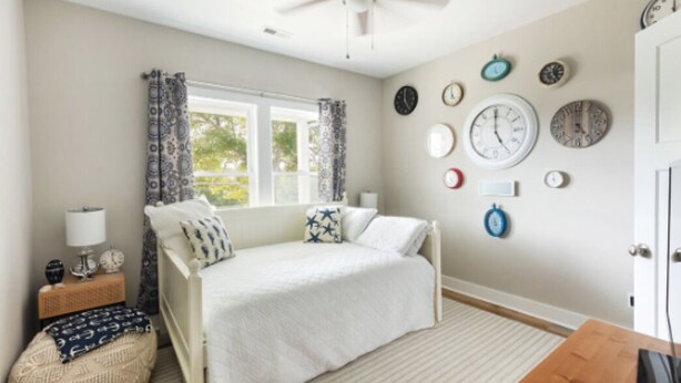 A bedroom with a bed, a window with curtains, a wall clock, and a bedside table. - Charming Oak Island Retreat — Minutes from the Beach with Private Hot Tub (Oak Island)