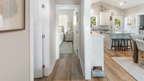 A spacious kitchen with a central island, wooden flooring, and white cabinetry. - Charming Oak Island Retreat — Minutes from the Beach with Private Hot Tub (Oak Island)