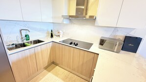 A modern kitchen with a stainless steel sink, a microwave, and wooden cabinets. - Vermare Bliss 2 Br private pool BBQ Cap Cana (Punta Cana)