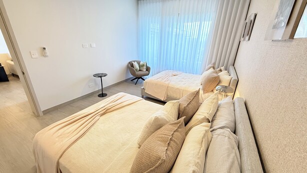 A hotel room with two beds, a small round table, a chair, and a window with curtains. - Vermare Bliss 2 Br private pool BBQ Cap Cana (Punta Cana)
