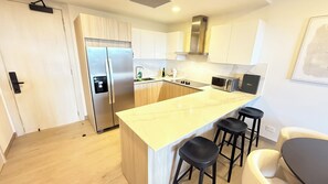 Eine moderne Küche mit einem Edelstahl-Kühlschrank, einer eingebauten Mikrowelle und einer Marmorarbeitsplatte.