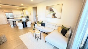 A modern living room with a sofa, coffee table, and a dining area with chairs and a table. - Vermare Bliss 2 Br private pool BBQ Cap Cana (Punta Cana)