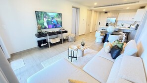Ein modernes Wohnzimmer mit einer Couch, einem Couchtisch und einem an der Wand befestigten Fernseher.