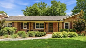 A two-story brick house with a front porch, a covered patio, and a well-maintained lawn. - 4Br Lux Stay w/Pool & Game Room - Sleeps 10 (Concord)