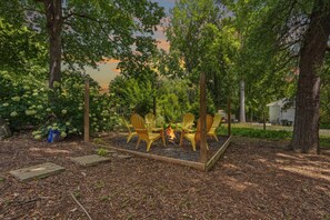 A fire pit with chairs in a wooded area.