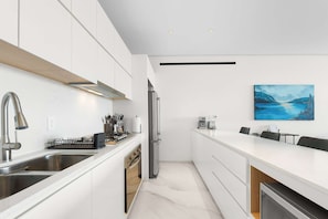 A modern kitchen with a built-in oven, stainless steel appliances, and a dining area with a view of the sea. - New Cabo Golf Retreat w/ Water Mirror Views (San José del Cabo)
