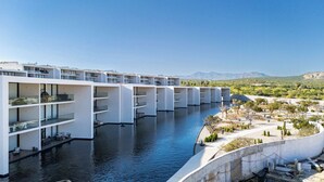 Un hotel moderno con varios pisos, una piscina y un paisaje desértico al fondo.