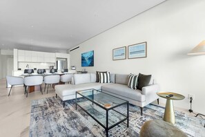 Ein modernes Wohnzimmer mit Glastisch, einer Couch und einem Essbereich mit Stühlen.