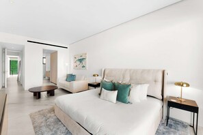A modern bedroom with a large bed, a sofa, a coffee table, and a painting on the wall. - New Cabo Golf Retreat w/ Water Mirror Views (San José del Cabo)