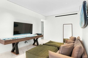 A modern living room with a flat-screen TV, a long wooden table, and a sofa with cushions. - New Cabo Golf Retreat w/ Water Mirror Views (San José del Cabo)