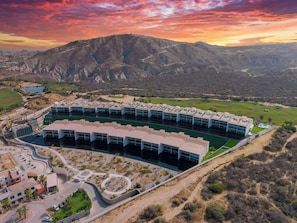 A modern hotel with a pool, surrounded by a landscaped area and mountains in the background. - New Cabo Golf Retreat w/ Water Mirror Views (San José del Cabo)