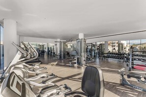 Ein modernes Fitnessstudio mit verschiedenen Trainingsgeräten, darunter Laufbänder, Kraftgeräte und Kurzhanteln.