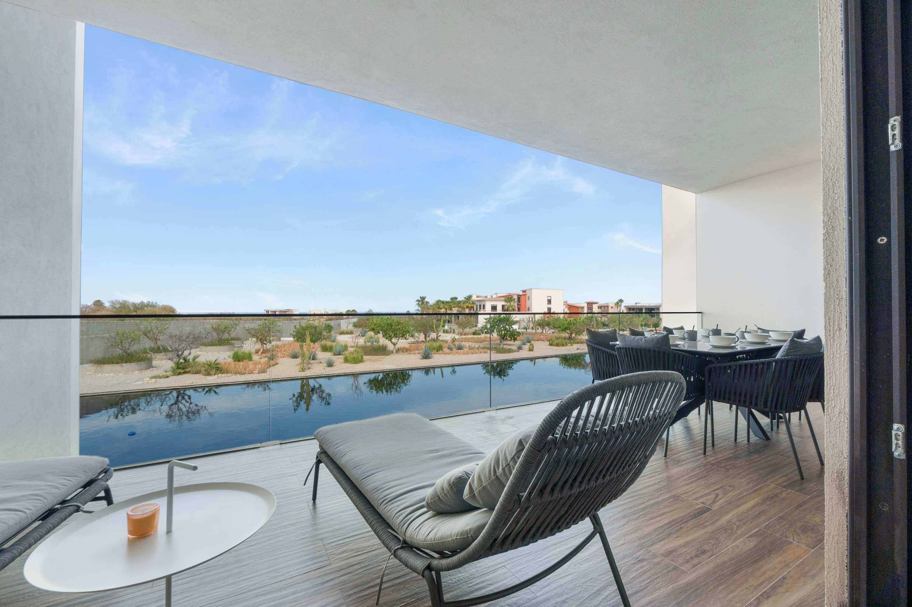 Un balcón con vista a una piscina y edificios al fondo.