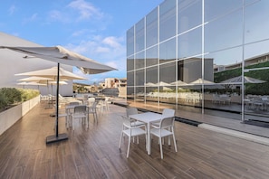 Eine Terrasse im Freien mit weißer Möbel, Sonnenschirmen und einem Pool.