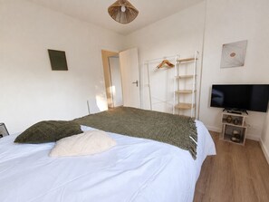 Ein Schlafzimmer mit einem Bett, einem Fernseher, einem Kleiderschrank und einer Tür zu einem anderen Raum.