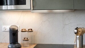 A modern kitchen with a coffee maker, two glass containers, a metal utensil holder, and a black induction cooktop. - Renovated Apartment in Quimper – 3 Bedrooms – Sleeps 6 (Quimper)