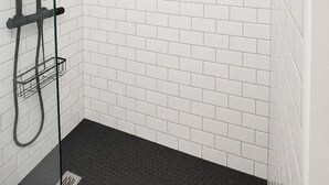 A shower area with white tiled walls and a black floor. - Renovated Apartment in Quimper – 3 Bedrooms – Sleeps 6 (Quimper)