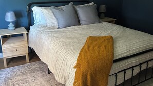 A bedroom with a bed, nightstands, a lamp, a framed picture of an elk, and a patterned rug.