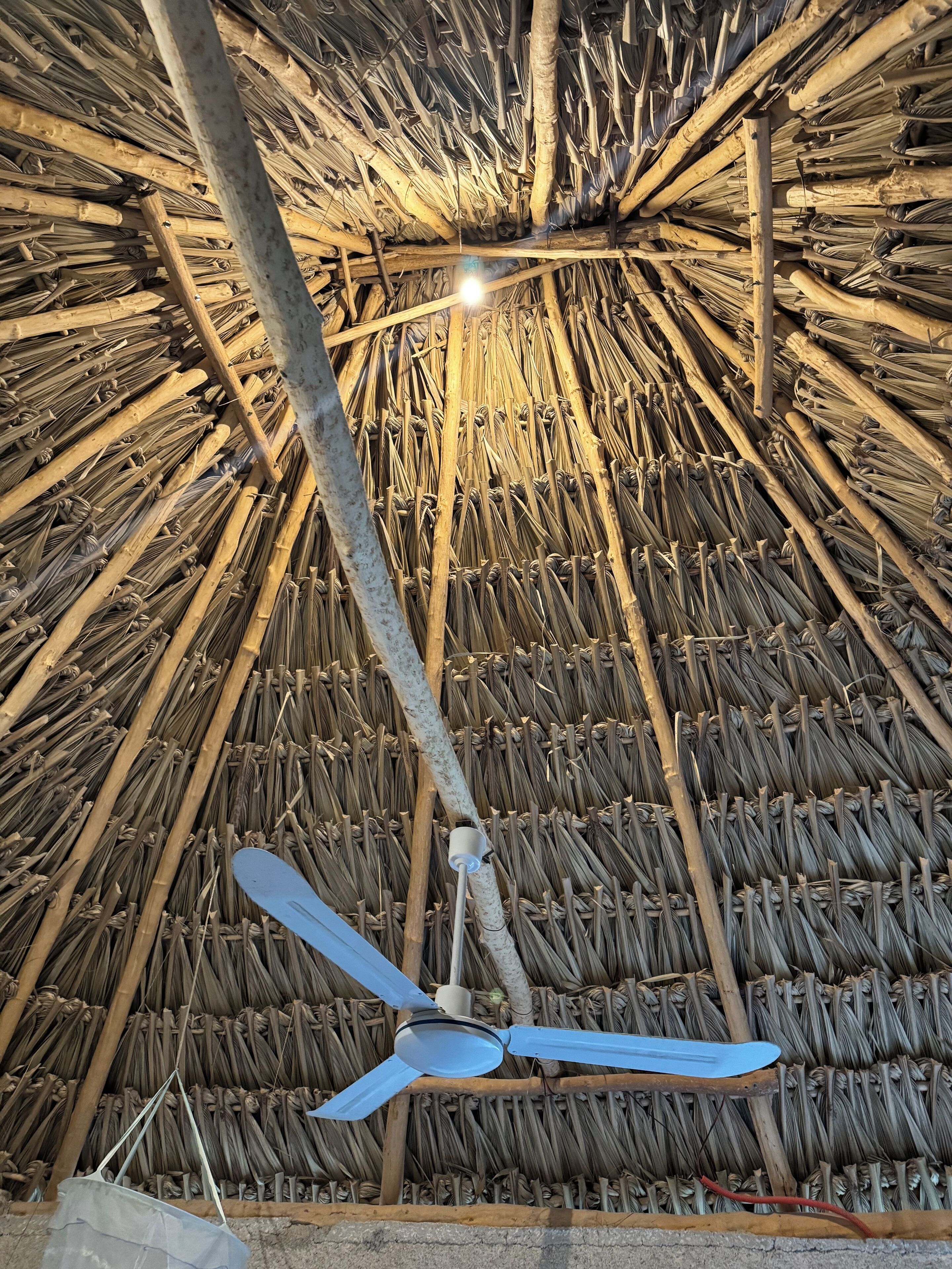 A room with a thatched ceiling and a ceiling fan.
