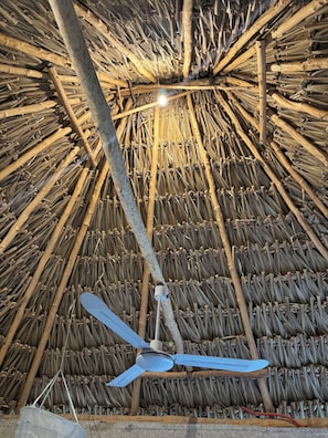 Una habitación con techo de paja y ventilador de techo.