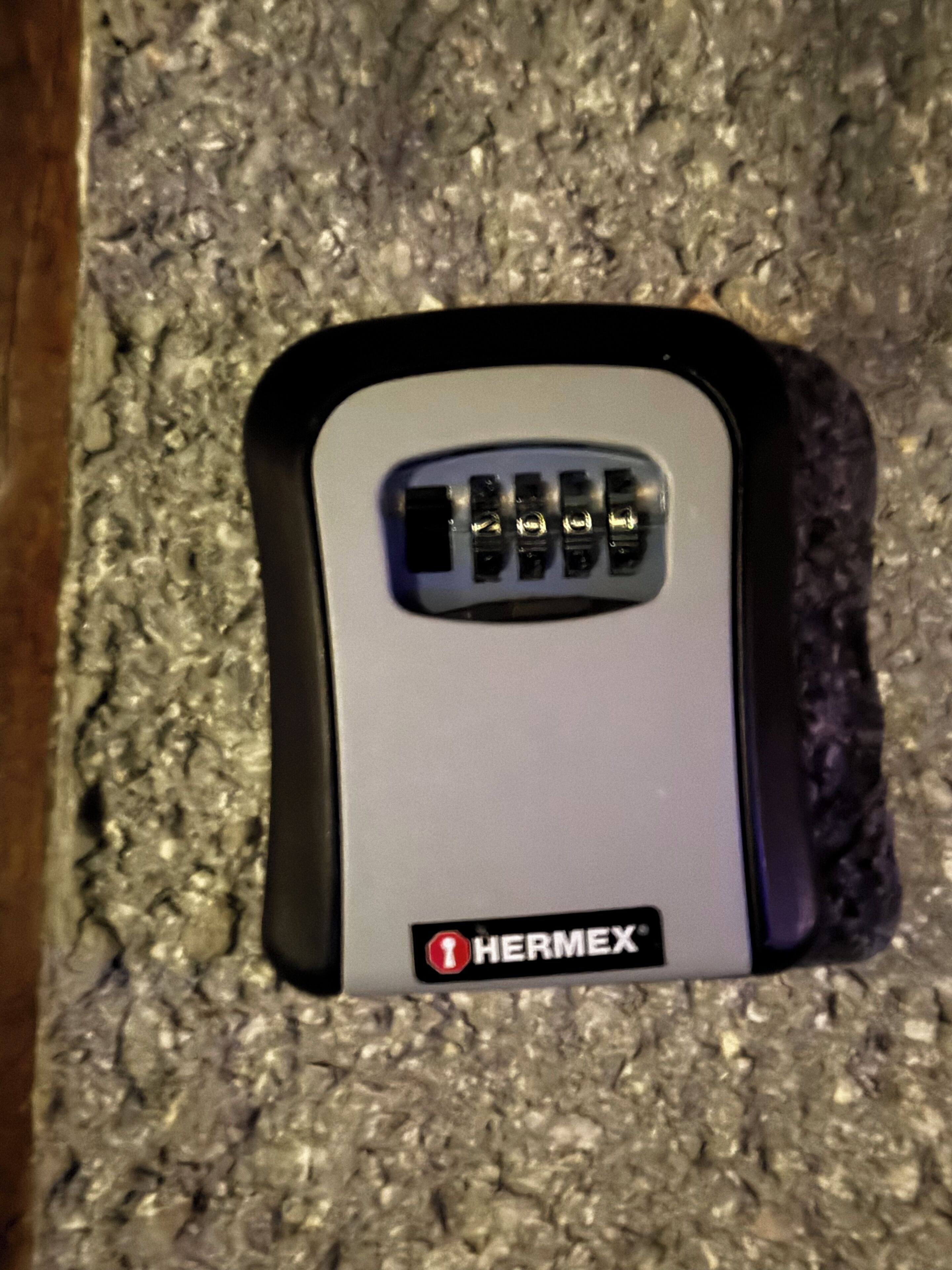 A Hermex brand device, possibly a security or access control system, installed in a textured wall.