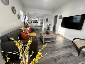 A modern living room with a sofa, coffee table, and a TV mounted on the wall. - Lovely Home in Little Havana- Near Loan Depot Park (Miami)