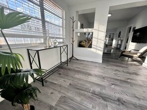 Ein modernes Interieur mit Holzboden, einem schwarzen Metallgeländer und einer großen Topfpflanze.
