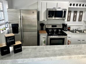 A modern kitchen with stainless steel appliances, a microwave, and a coffee maker. - Lovely Home in Little Havana- Near Loan Depot Park (Miami)