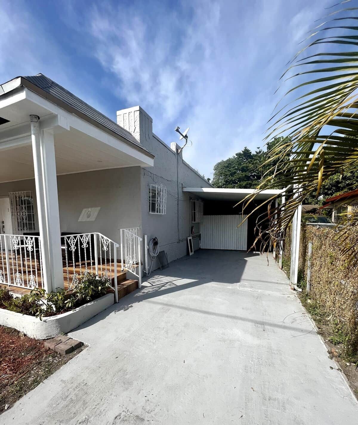 A residential property with a covered driveway, a garage, and a fenced yard.