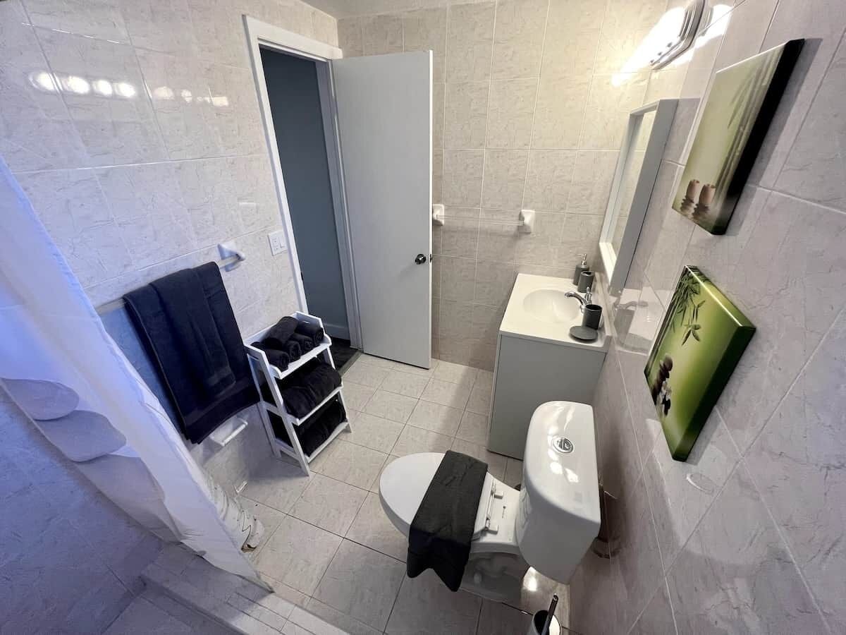 Un baño con inodoro, lavamanos y un perchero para toallas.