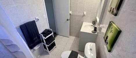 Un baño con inodoro, lavamanos y un perchero para toallas.