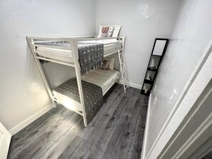 A bunk bed with a ladder, a small bedside table, and a mirror on the wall. - Lovely Home in Little Havana- Near Loan Depot Park (Miami)