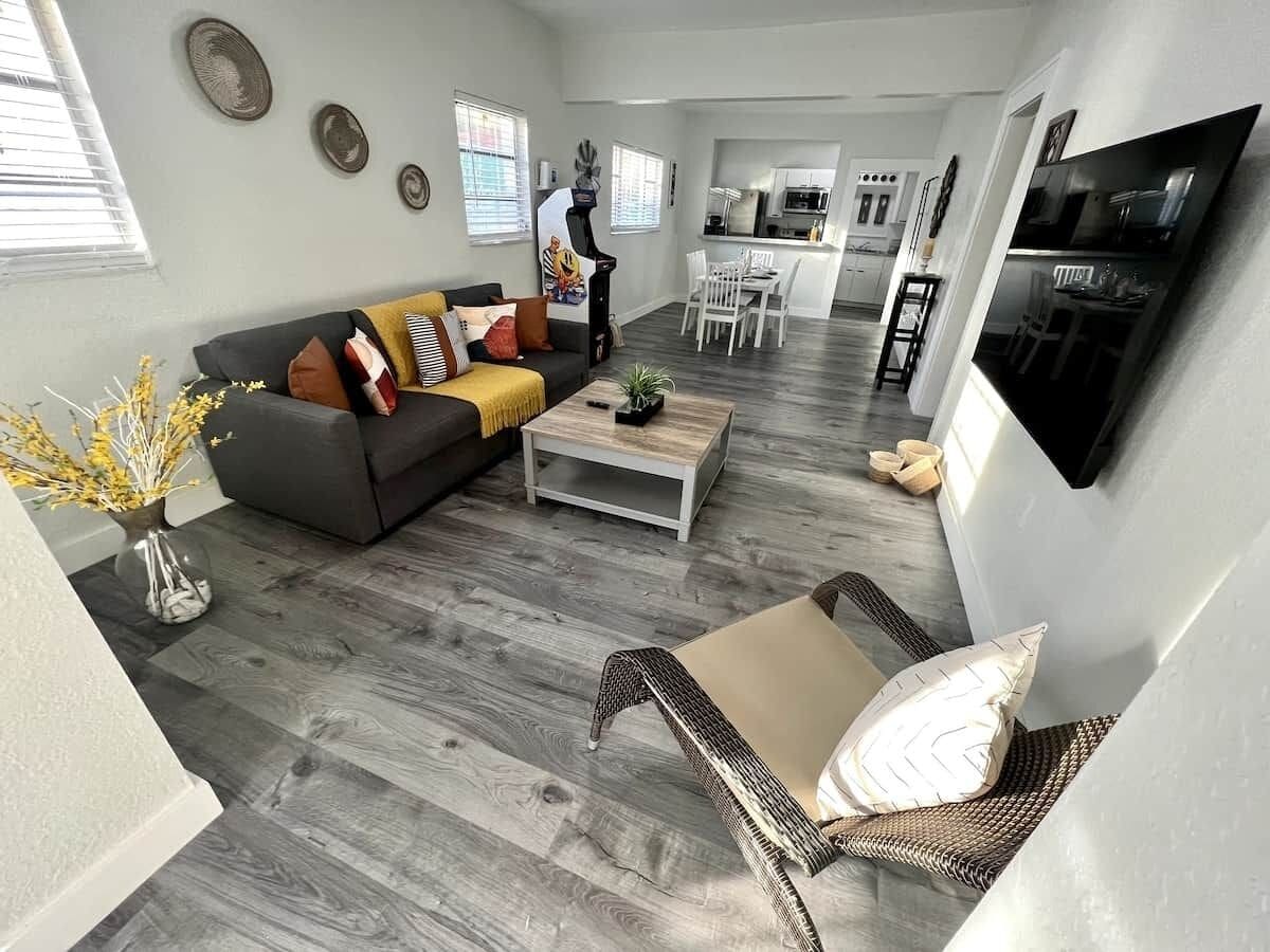 Una sala de estar moderna con un sofá gris, una mesita de centro y un sillón de mimbre.