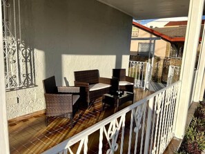 Ein Balkon mit Korbmöbeln und einer weißen Brüstung.
