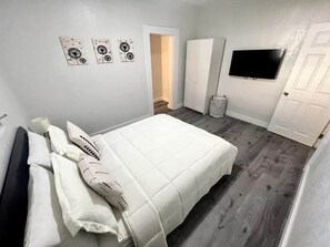 Ein Schlafzimmer mit Bett, Fernseher, Kleiderschrank und Tür.