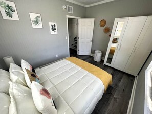 Ein Schlafzimmer mit einem Bett, Kissen, einem Kleiderschrank und Wandbildern.