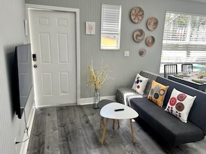 A living room with a grey sofa, a white coffee table, a door, and a wall-mounted TV. - Modern Apartment near Brickell & Coral Gables 1 (Miami)