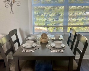 A dining table set for six with white plates and glasses, positioned near a window with blinds. - Modern Apartment near Brickell & Coral Gables 3 (Miami)