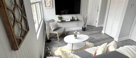 Un salon moderne avec un canapé, une table basse ronde et un téléviseur fixé au mur.
