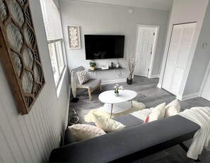 Un salon moderne avec un canapé, une table basse ronde et un téléviseur fixé au mur.