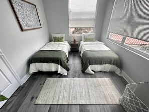 Ein Schlafzimmer mit zwei Betten, einem Teppich und einem an der Wand befestigten Bild.