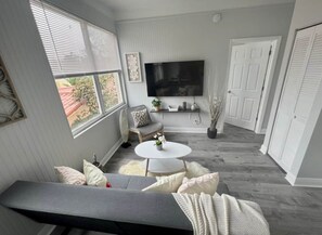 Ein Wohnzimmer mit grauem Sofa, einem weißen Couchtisch und einem an der Wand befestigten Flachbildfernseher.