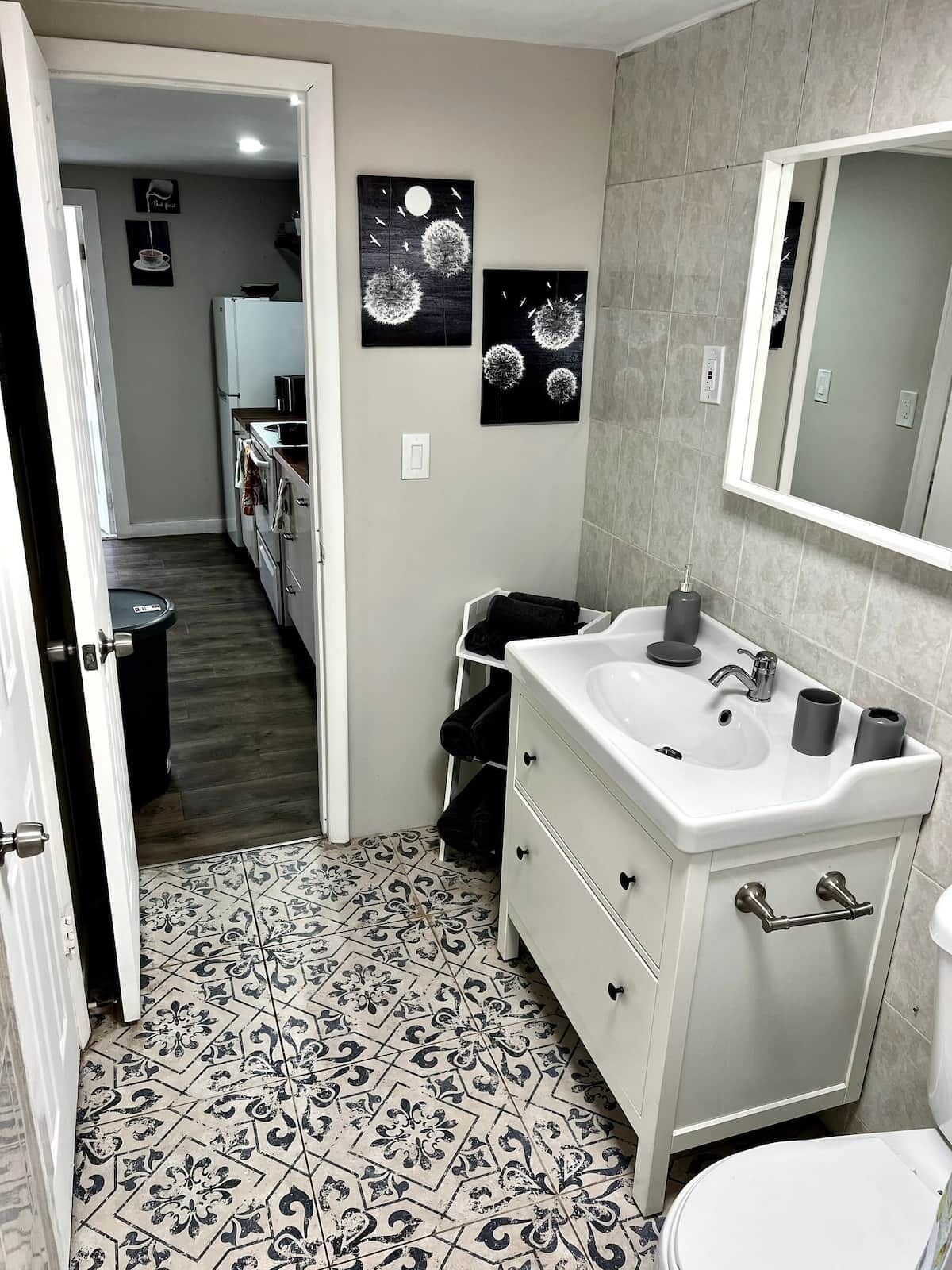 A bathroom with a white sink, mirror, and patterned floor tiles.