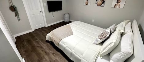 A bedroom with a bed, a television, and wall art.