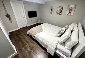 Ein Schlafzimmer mit einem Bett, einem Fernseher und Wandbildern.