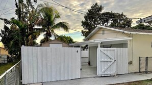 A residential property with a gated driveway, a covered garage, and a small house.