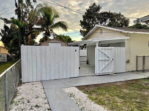 A residential property with a gated driveway, a covered garage, and a small house.