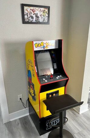 Ein Pac-Man-Automata in einem Raum mit schlichter Wand und einem gerahmten Bild darüber.