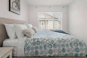 A bedroom with a bed, pillows, a headboard, a window with blinds, and a framed picture on the wall. - King Bed | Close to Airport | 6 Guests (Calgary)